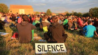 Taizé – Jugendlcihe auf einer Wiese zur Geburtstagsfeier von Bruder Roger, davor eni Schild "Silence"; © dpa/Catherine Leblanc/Godong