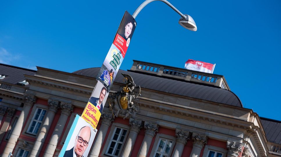 Plakate verschiedener Parteien hängen an einer Straßenlaterne vor dem Brandenburger Landtag