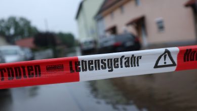 "Lebensgefahr" ist auf einem Absperrband vor einer von der Mindel überfluteten Straße zu lesen. © picture alliance/dpa/Karl-Josef Hildenbrand