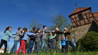 Einwohner von Reichenwalde (Landkreis Oder-Spree) nahe Storkow (Brandenburg) stützen am 17.04.2014 symbolisch den schrägen Turm der kleinen Dorfkirche; © picture alliance/dpa/Patrick Pleul