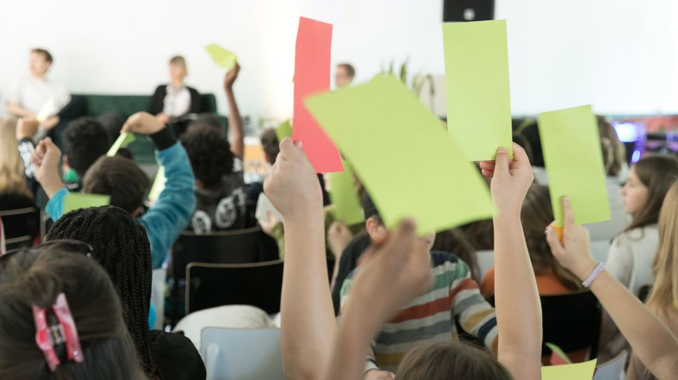 Diskussion zum Thema Demokratie in Schule: Zustimmung grün, Ablehnung rot, München 2024; © picture alliance/SZ Photo/Florian Peljak