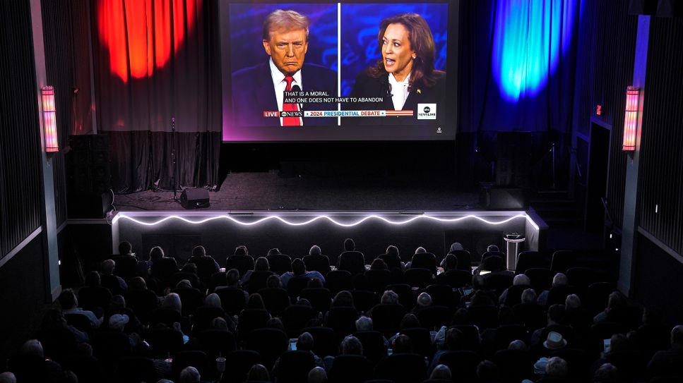 Zuschauer gucken die Debatte zwischen Donald Trump und Kamala Harris in einem Saal © picture alliance / AP/ Charlie Riedel