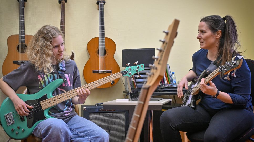 Schülerin übt mit Musiklehrerin E-Bass an der Städtischen Musikschule "Johann Crüger" in Guben © Patrick Pleul / picture alliance/dpa