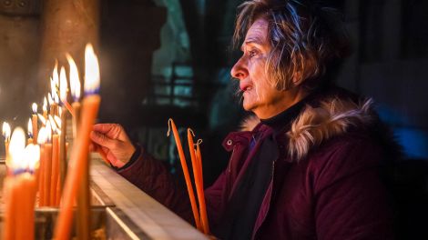 Frau zündet Kerzen in der Grabeskirche an, Jerusalem 14.12.2023; © picture alliance/Middle East Images/ABACA