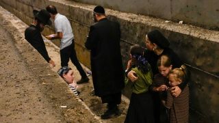 Raktetenangriff aus dem Iran: Menschen suchen Schutz an einer Mauer, Jerusalem 01.10.2024; © picture alliance/AP/Ohad Zwigenberg