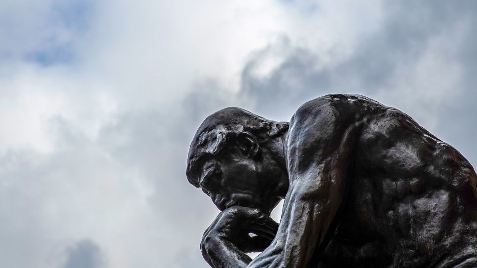 Die Plastik "Der Denker" ("Le Penseur") des Bildhauers Auguste Rodin ist vor einem wolkenverhangenen Himmel zu sehen; © picture alliance/dpa/Friso Gentsch