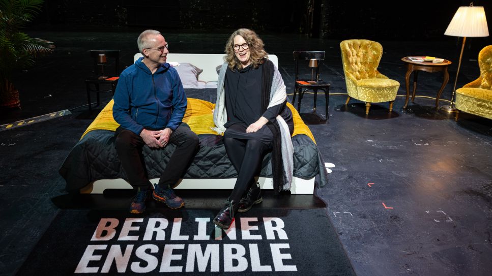 Stefanie und Christoph Siegmann sitzen auf einem Bett auf der Bühne im Berliner Ensemble; © picture alliance/dpa/Hannes P. Albert