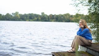Nachrichtenmüdigkeit: Frau sitzt auf einem Bootssteg – Symbolfoto Eskapismus; © imago-images.de/Westend61
